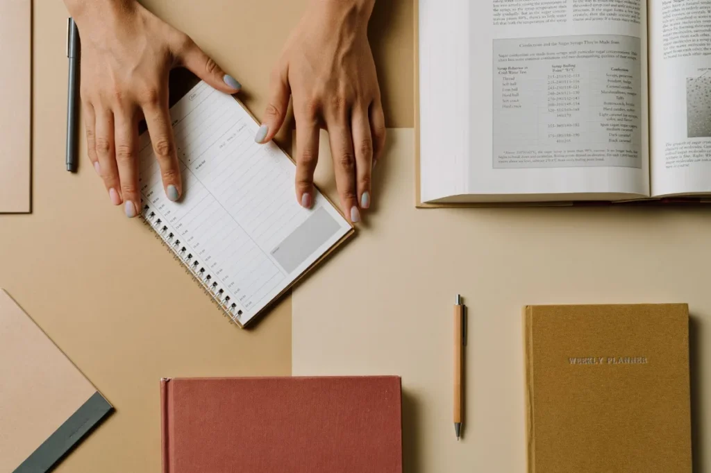 Buku terbuka dan agenda mingguan di meja kerja untuk merencanakan kebiasaan membaca