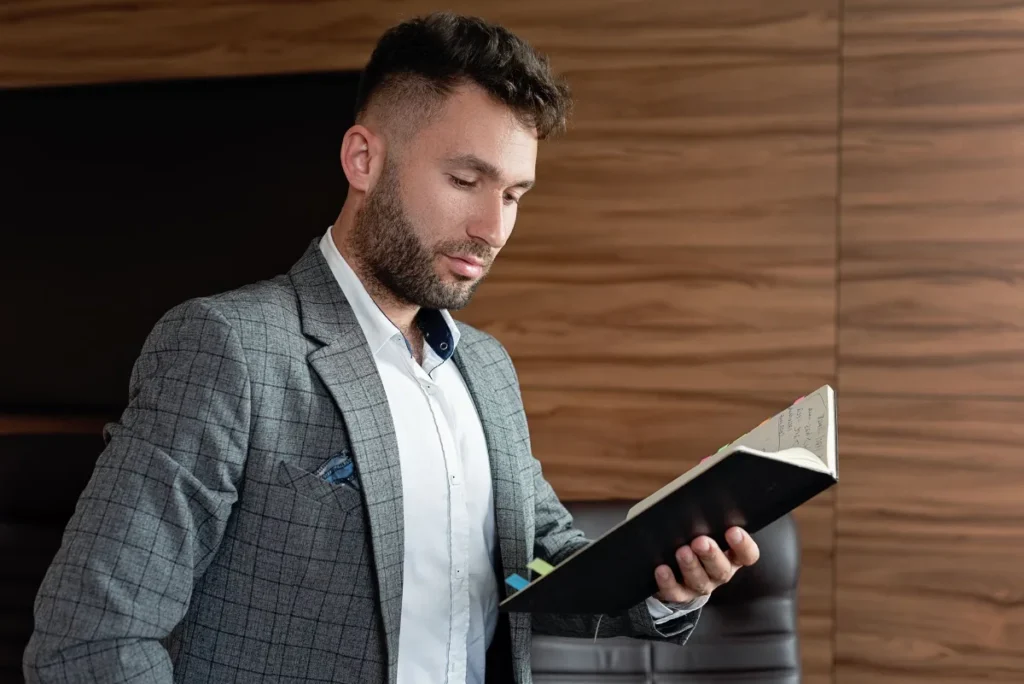 Profesional muda membaca buku bisnis dan menyiapkan catatan eksperimen kerja