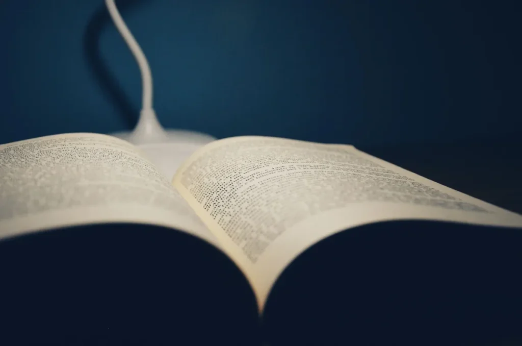 Buku terbuka di meja dengan lampu baca dalam suasana malam yang tenang